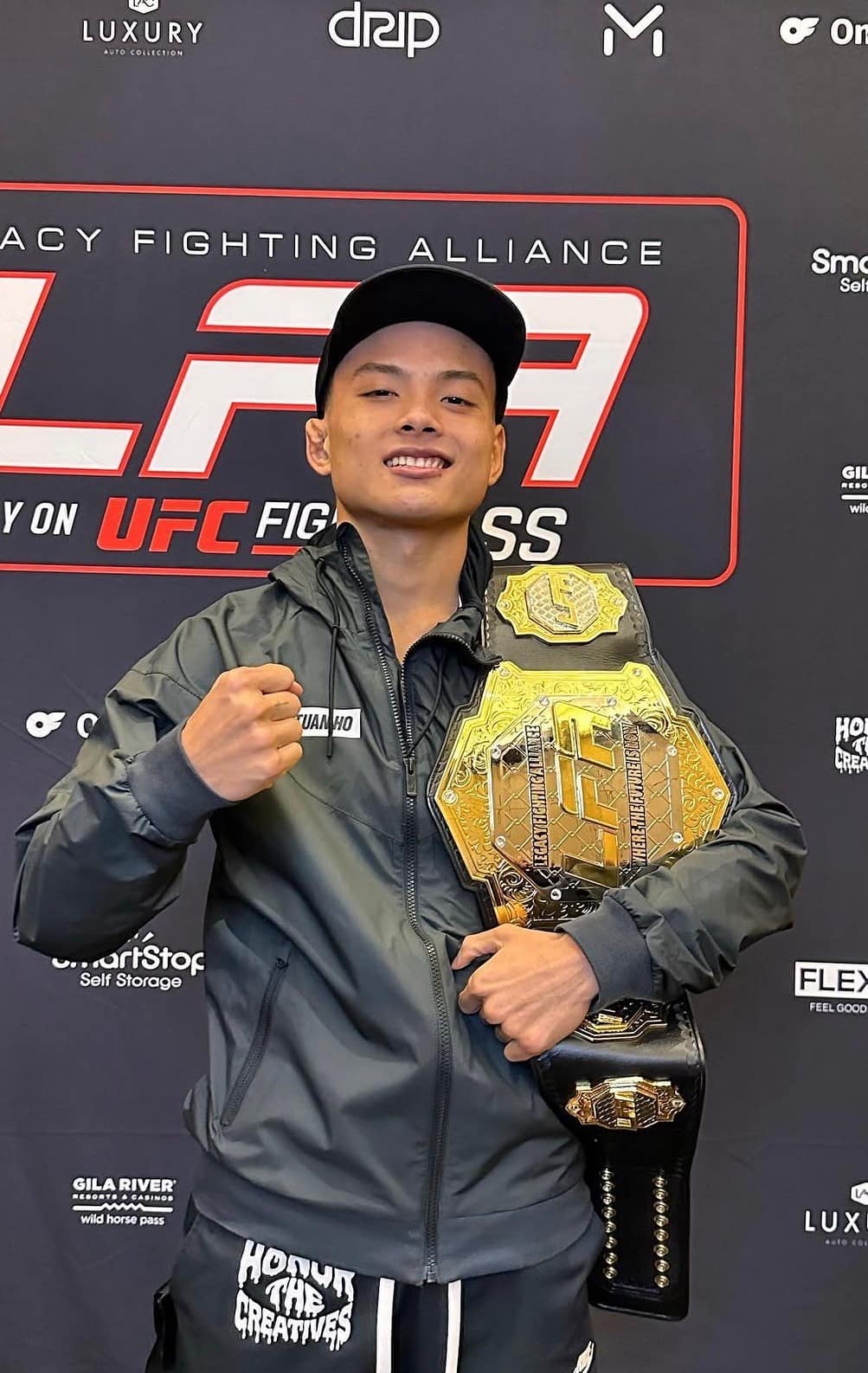 Hồ Tuấn An holding the LFA championship belt at a Legacy Fighting Alliance event